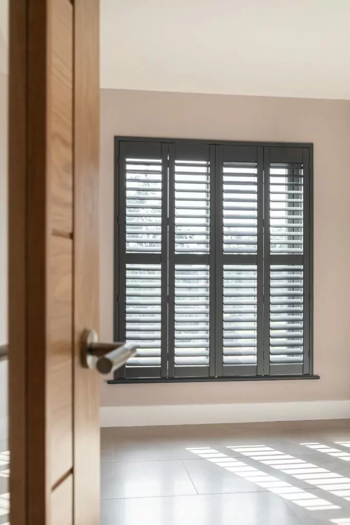 View into room with Basalt Grey Painted Plantation Shutters in Living Room - Village Blinds and Shutters Northern Ireland